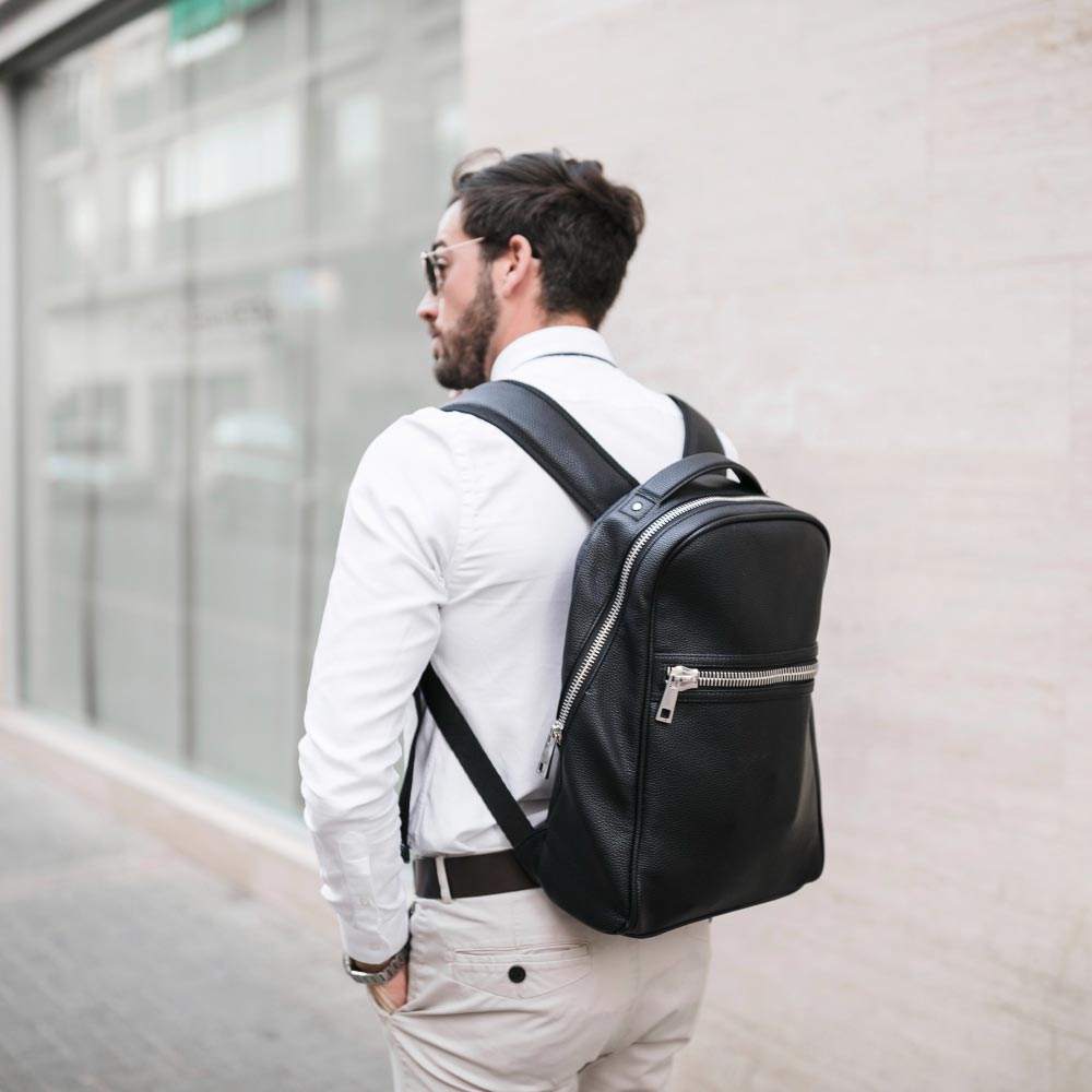 Men’s black gym backpack with multiple compartments displayed on a concrete urban backdrop