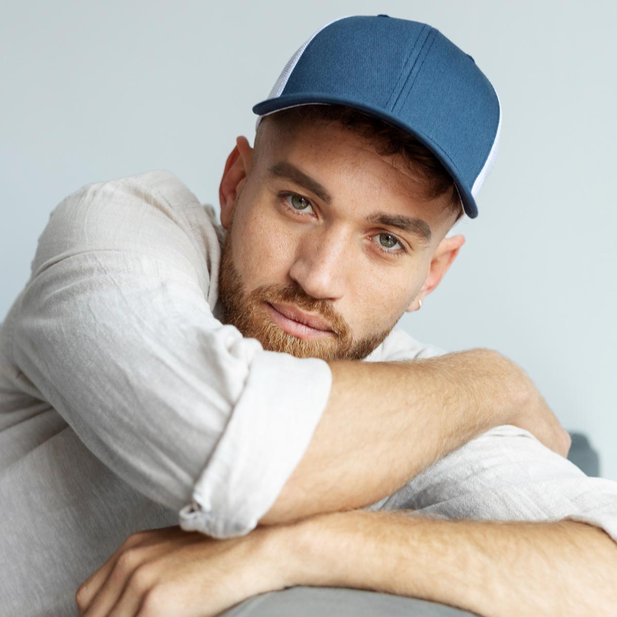 Men’s blue baseball cap with Luvuma logo on a minimalist concrete background